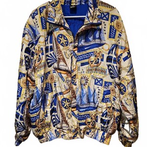 May include: A vintage jacket with a nautical theme. The jacket features a cream-colored background with blue and yellow sailboat, anchor, and compass designs. It has a full zipper, a blue interior lining, and is hanging on a white hanger.