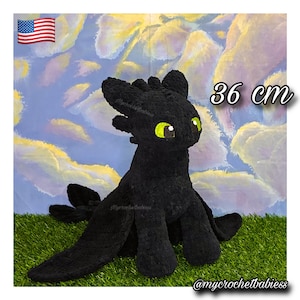 May include: A black crochet plush toy resembling a dragon with large pointed ears, textured fur, and bright green eyes. The plush measures 36 cm in height. The text 'mycrochetbabiess' is visible on the body and in the bottom right corner.