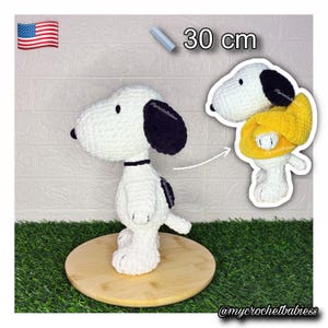 May include: A white and black crocheted plush toy resembling a beagle, standing 30 cm tall. The toy features a black ear, a black collar, and a small tail. A second view shows the same plush toy wearing a bright yellow sweater over its body.