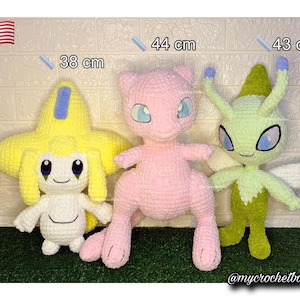 May include: Three crocheted Pokémon plushies: a yellow and blue Jirachi (38 cm), a pink Mew (44 cm), and a green Celebi (43 cm). The plushies are handmade and sit on a green surface. The American flag is in the top left corner.