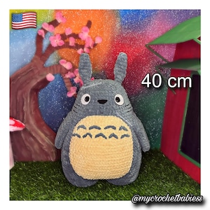 May include: A gray and beige plush toy featuring a rounded body, two tall ears, and a cream-colored belly with dark gray chevron markings. The toy has black oval eyes and a small nose. The text 40 cm is visible, indicating a height of 15.75 inches.
