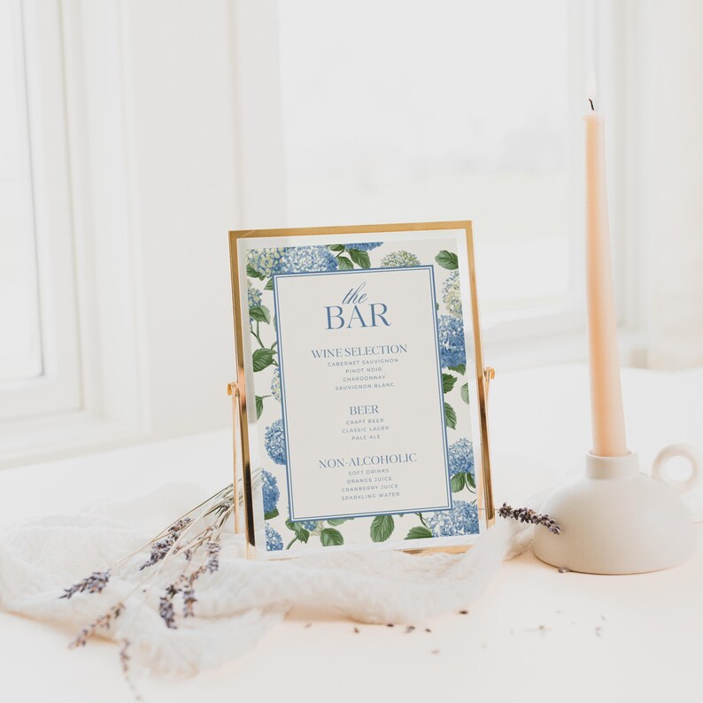 Elegant blue hydrangea wedding bar menu sign featuring soft blue hydrangea florals and greenery surrounding a classic framed drink menu layout. Floral bar menu sign designed for wedding receptions, garden weddings, and elegant outdoor celebrations. Editable and printable Canva template perfect for hydrangea themed weddings, blue floral wedding decor, signature drink menus, and sophisticated wedding bar signage.