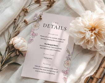 May include: A blush pink wedding details card with floral accents and the text "THE DETAILS". The card includes information about the reception, dress code, and parking. Decorative flowers and fabric surround the card.