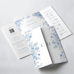 Elegant dusty blue toile gatefold wedding invitation with a classic French toile floral pattern in soft blue on an ivory background. The tri-fold gatefold design opens to reveal the main invitation centered with refined serif typography and a delicate script accent. The left interior panel includes an RSVP section with QR code, venue, accommodations, and transportation details, while the right panel displays a wedding day timeline with minimal line icons. Editable printable Canva template.