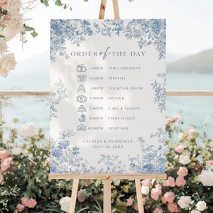 Può includere: Un cartello nuziale bianco su un cavalletto con dettagli floreali blu e la scritta "ORDER OF THE DAY". Il cartello mostra il programma della cerimonia, tra cui la cerimonia, le foto, l'aperitivo, la cena, la torta, il primo ballo e il congedo. Sono inclusi anche i nomi Cecilia & Harrison e la data.