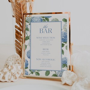 Elegant blue hydrangea wedding bar menu sign featuring soft blue hydrangea florals and greenery surrounding a classic framed drink menu layout. Floral bar menu sign designed for wedding receptions, garden weddings, and elegant outdoor celebrations. Editable and printable Canva template perfect for hydrangea themed weddings, blue floral wedding decor, signature drink menus, and sophisticated wedding bar signage.
