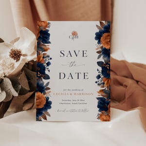 May include: A rectangular wedding invitation with the text "SAVE THE DATE" in black script. The invitation is bordered with navy blue and orange floral arrangements. The wedding details include the names Cecilia & Harrison, the date, and location.