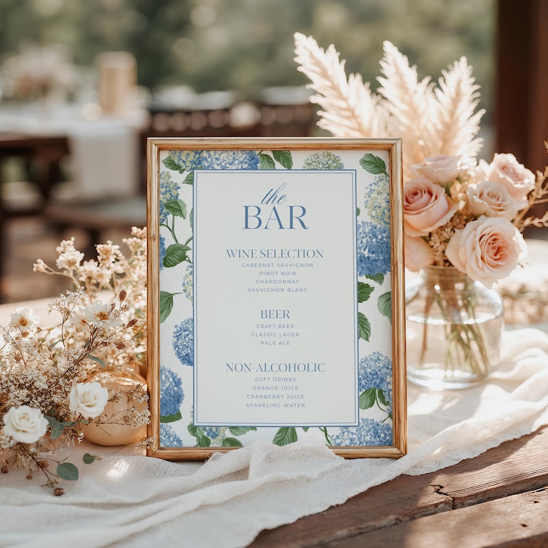 Elegant blue hydrangea wedding bar menu sign featuring soft blue hydrangea florals and greenery surrounding a classic framed drink menu layout. Floral bar menu sign designed for wedding receptions, garden weddings, and elegant outdoor celebrations. Editable and printable Canva template perfect for hydrangea themed weddings, blue floral wedding decor, signature drink menus, and sophisticated wedding bar signage.