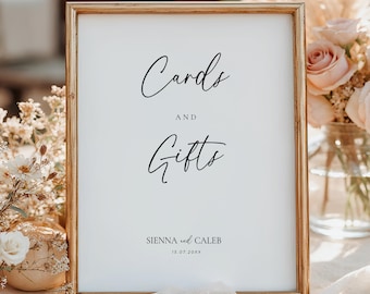 May include: A framed sign with the words "Cards and Gifts" in elegant script. The sign is in a gold frame and includes the names "Sienna and Caleb" and a date. The background features floral arrangements.