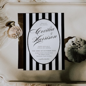 Op de afbeelding: Een trouwuitnodiging met zwart-witte strepen, met de namen "Cecilia & Harrison" in sierlijke letters. De uitnodiging bevat de datum, tijd en locatie van de bruiloft. Een parfumflesje en een decoratief bord zijn ook zichtbaar.
