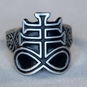 Puede incluir: Un anillo de plata con un diseño de esmalte negro en forma de cruz y símbolo de infinito.