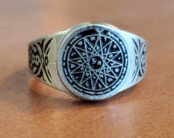 May include: A silver ring with a circular design featuring a star with eight points and Hebrew characters around the perimeter.
