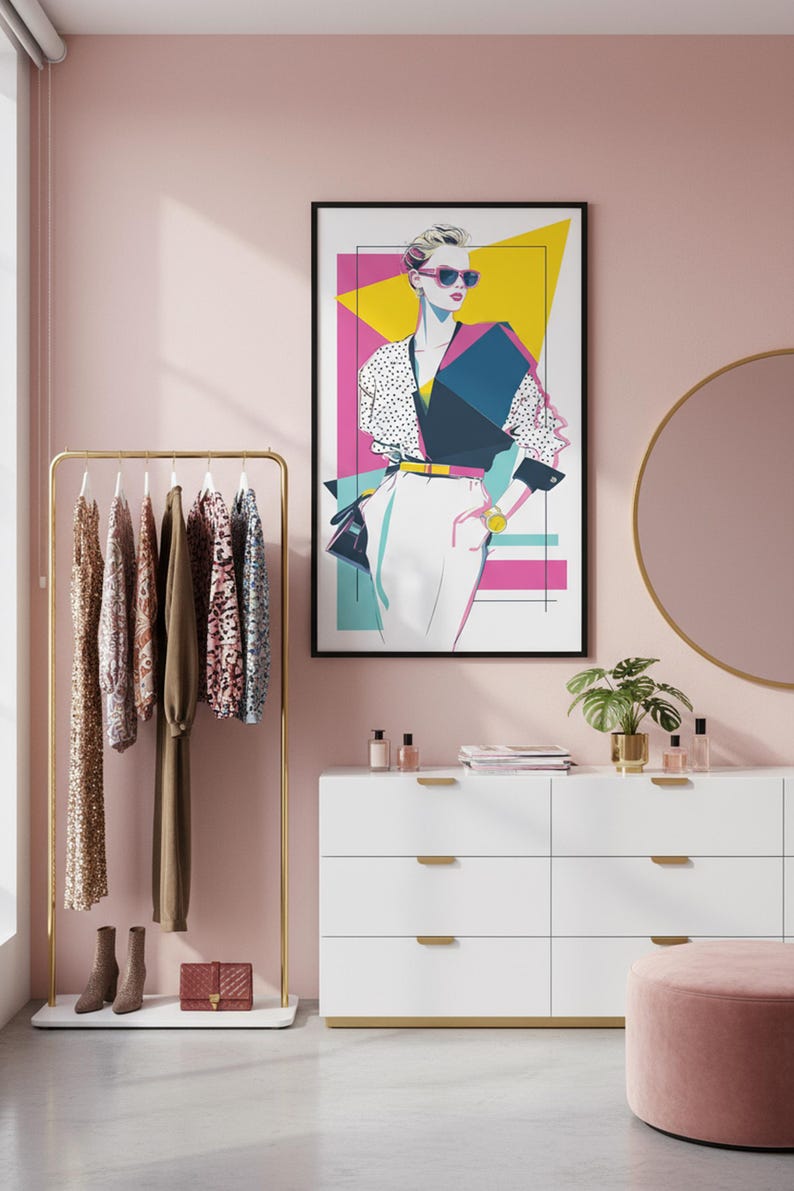 May include: A framed art print of a stylish person in sunglasses, wearing a polka dot top and white pants. A gold clothing rack with dresses and a white dresser with gold accents are also in the room. A pink ottoman and a round mirror complete the scene.
