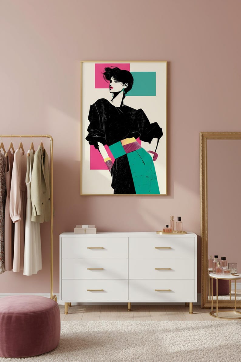 May include: A framed art print featuring a stylized illustration of a person in a black top, teal skirt, and a pink and teal background. The artwork is displayed above a white dresser with gold hardware.