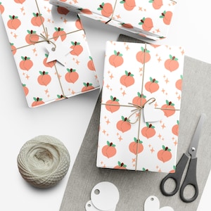 May include: Gift-wrapped presents with a peach pattern on white paper, tied with twine and a tag. A ball of twine, scissors, and blank tags are also visible. The peach design includes orange peaches with green leaves and small star accents.