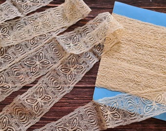May include: Beige lace trim with a butterfly design. The lace is delicate and intricate, with a soft, flowing texture.
