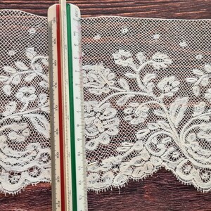 Puede incluir: Ribete de encaje marfil con dise&ntilde;o floral, con hojas y flores detalladas. Una regla muestra el ancho del encaje. El encaje tiene un borde festoneado y un tejido abierto y delicado, adecuado para proyectos de manualidades. El encaje mide unos 10 cm de ancho.