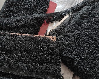 May include: Black fringe trim with a textured, woven design. The trim is made of a soft, pliable material and has a subtle sheen.