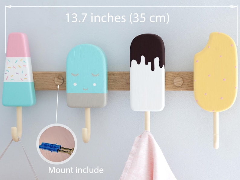May include: A wooden wall-mounted coat rack featuring four colorful popsicle-shaped hooks. The rack is 13.7 inches (35 cm) wide and includes mounting hardware. The hooks are painted in pastel colors with decorative details.