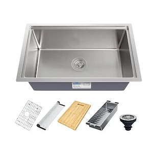 Puede incluir: Un fregadero de cocina de acero inoxidable con un solo cuenco y un desag&uuml;e en el centro. El fregadero est&aacute; rodeado por una encimera blanca e incluye una variedad de accesorios, como una tabla de cortar, un escurridor, un escurridor de platos y un colador.