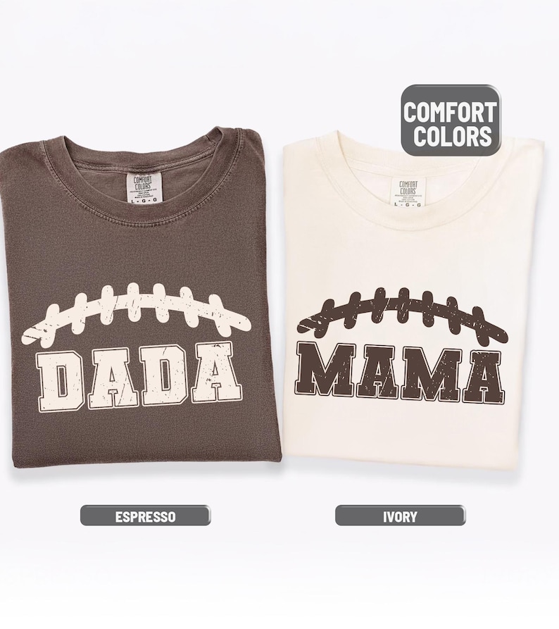 Puede incluir: Dos camisetas dobladas, una espresso y otra marfil, cada una con un dise&ntilde;o de f&uacute;tbol americano. La camiseta espresso dice "DADA" y la camiseta marfil dice "MAMA". Las camisetas tienen la leyenda "COMFORT COLORS".