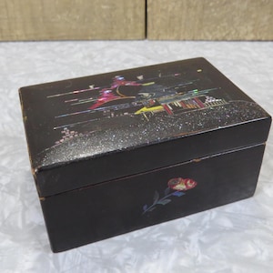 May include: A rectangular black jewelry box with a decorative lid featuring an iridescent design. The box has a rose painted on the front. The box is made of wood.