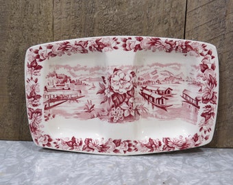 May include: A white ceramic serving dish with a red floral design and a scene of boats on a lake. The dish is divided into three sections.