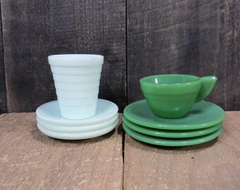 May include: A set of two vintage teacups and saucers. The teacup and saucer on the left are light blue, while the teacup and saucer on the right are green.