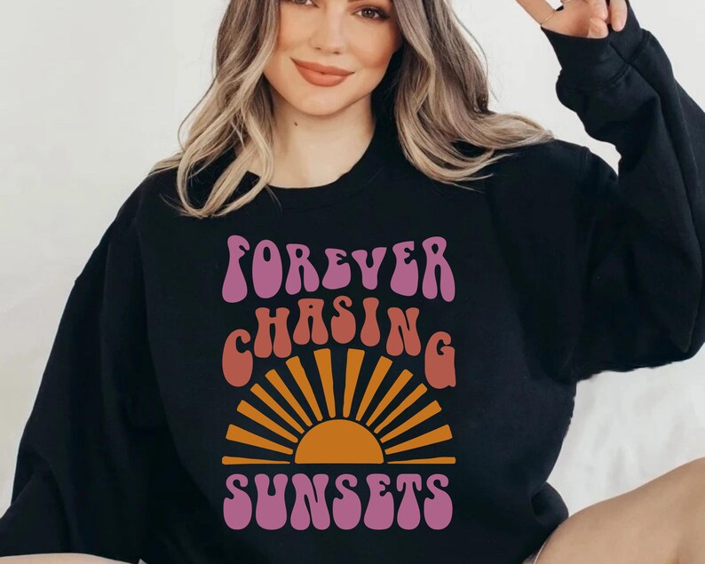 May include: Black sweatshirt with a pink, orange and yellow graphic design that says "FOREVER CHASING SUNSETS" in a retro font.
