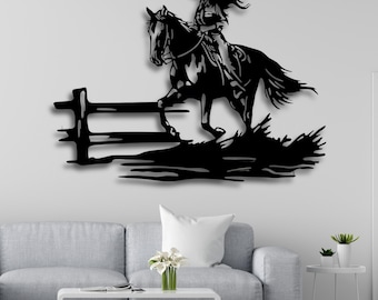 May include: Black metal wall art depicting a cowgirl riding a horse over a fence. The silhouette design is perfect for a western-themed home decor.
