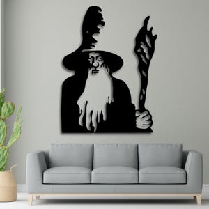 May include: Black silhouette wall art of a wizard with a long beard and pointed hat holding a staff. The wizard is facing forward with a serious expression.