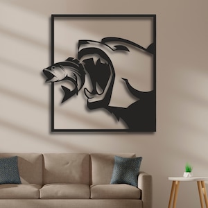 May include: Black metal wall art depicting a bear with its mouth open, about to eat a fish. The bear and fish are in silhouette against a white background.