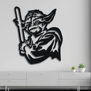 May include: Black and white silhouette wall art of Yoda from Star Wars holding a lightsaber.