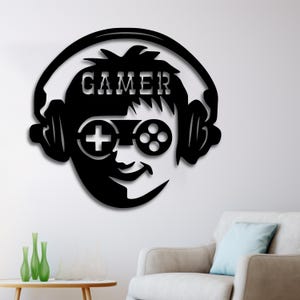 Op de afbeelding: Zwarte en witte silhouet van een persoon met een koptelefoon en een videogamecontroller als bril. Het woord "GAMER" staat boven het hoofd van de persoon.