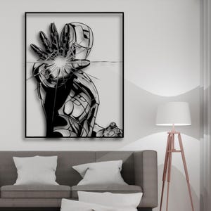 Può includere: Arte da parete in metallo bianco e nero con un personaggio di supereroe con un'esplosione di energia incandescente. L'opera è incorniciata in una cornice nera.