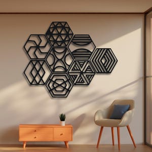 Puede incluir: Decoración de pared geométrica negra hecha de hexágonos de metal con diferentes patrones. La decoración está montada en una pared beige en un salón.