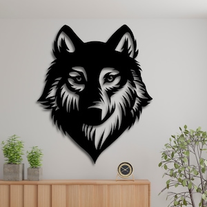 Könnte beinhalten: Schwarze Wandkunst aus Metall mit einem Wolfskopf mit filigranen Details. Der Wolfskopf ist nach vorne gerichtet, die Augen sind offen und der Mund geschlossen. Die Kunst ist an einer weißen Wand montiert.