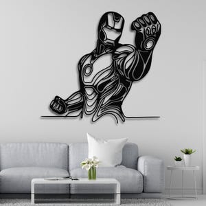 May include: Black metal wall art depicting a stylized Iron Man figure with a raised fist. The figure is outlined in a series of intricate lines.