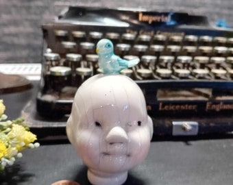 Doll head sculpture with bird