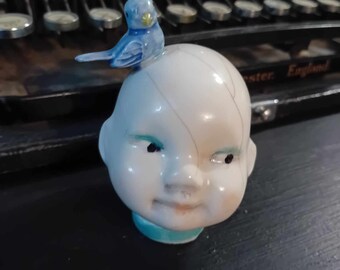 Doll head sculpture with bird