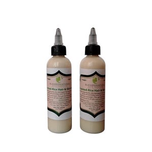 May include: Two clear glass bottles with black caps and labels. The labels are white with green accents and text that reads "Blessed Natural Hair Products Fermented-Rice Hair & Skin Serum". The bottles are filled with a light-colored liquid.