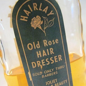 May include: A vintage glass bottle of "Old Rose Hair Dresser." The label is dark green with gold lettering and a rose illustration. The bottle contains a golden-colored liquid and is partially visible.