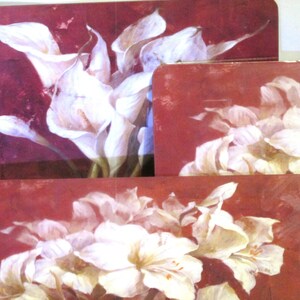 May include: Set of four red and white floral coasters featuring white calla lilies and white amaryllis flowers.