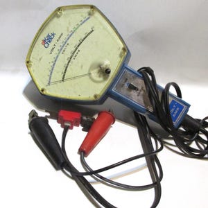 May include: Vintage "Kar Check" volt-amp meter with a clear plastic face and a blue and yellow body. The meter has a needle and a dial for measuring voltage and amperage. Includes black and red test leads.