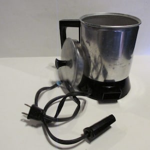 May include: A vintage silver electric coffee percolator with a black cord and plug. The percolator has a black handle and a lid with a knob.