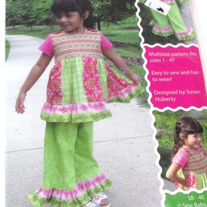 May include: Sew Baby! pattern for a twirl top and pants for sizes 1-4T. The pattern features a girl wearing a green and pink top with a ruffle trim and matching green pants with a ruffle trim. The pattern is easy to sew and fun to wear. Designed by Susan Huberty.