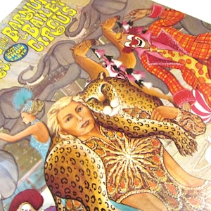 May include: A vintage circus poster featuring a woman in a leopard print costume with a cheetah, a clown, and elephants. The poster reads "Ringling Bros. and Barnum & Bailey Circus The Greatest Show on Earth".