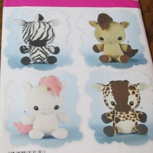 May include: A sewing pattern for making four stuffed animal toys: a zebra, a horse, a unicorn, and a giraffe. The pattern is from Simplicity and is for one size. The pattern is printed on a white background with a pink border.