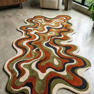 Peut inclure: Tapis abstrait au motif ondulé et organique. Le design du tapis combine des teintes de rouille orangée, vert olive, crème et bleu marine. Sa forme irrégulière accentue son attrait contemporain. Un élément décoratif pour un salon, mesurant environ 200 cm x 300 cm.