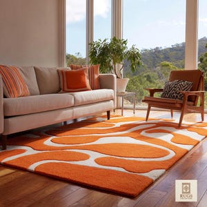 May include: A vibrant orange and white abstract rug in a living room. The rug's design is echoed by orange cushions on a beige sofa. A wooden armchair and large windows with a view of a green landscape complete the scene. The room has a modern feel.